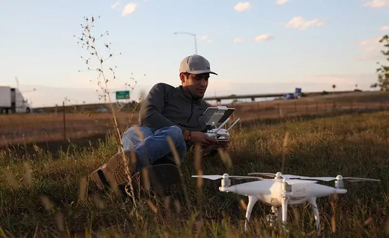 Man with gray hat in field using a drone