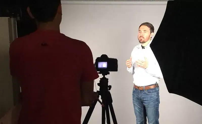 Man getting video recorded on gray background