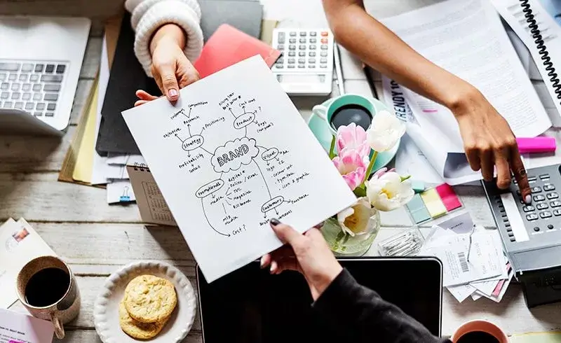 A group of people at a messy table with a sheet of paper on branding