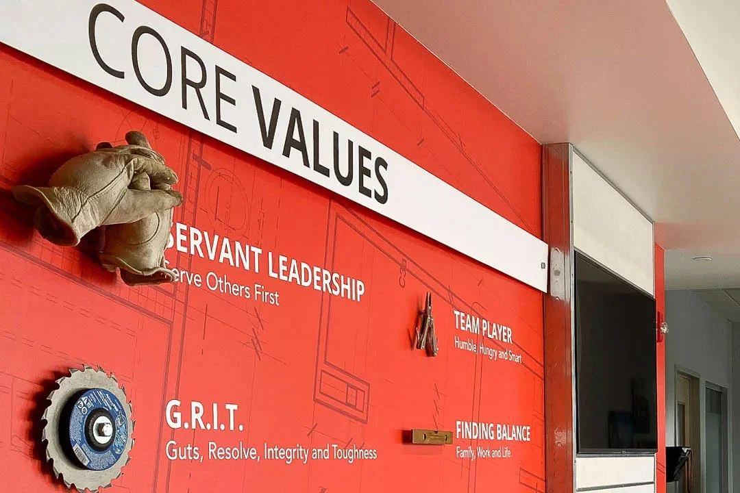 A red wall with tools and core values on it