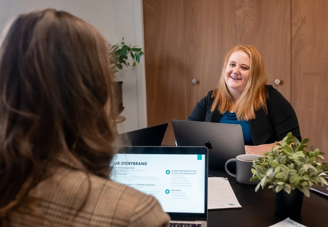 Two women working at a table together on laptops